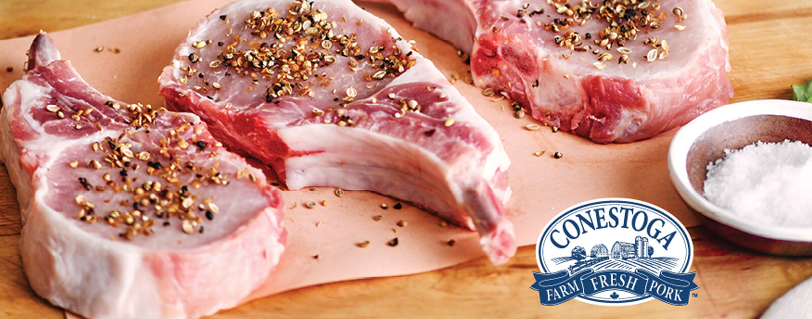Fresh Canadian Conestoga Meats seasoned pork chops on a wooden board